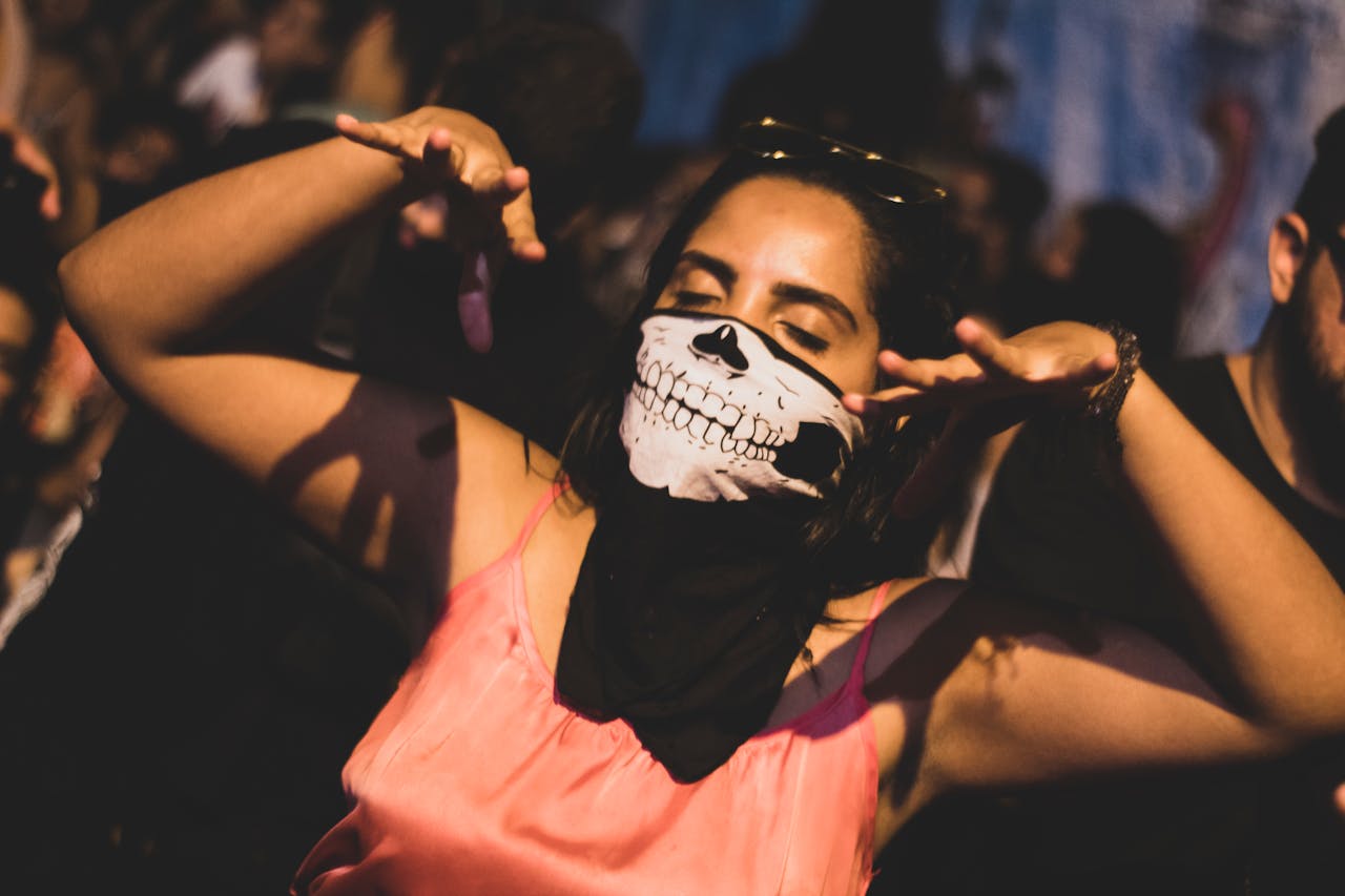 Woman wearing a skeleton face mask dancing at an outdoor music festival.