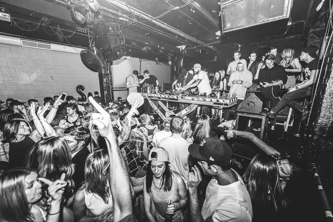 Vibrant nightclub scene with DJ and dancing crowd enjoying live music.